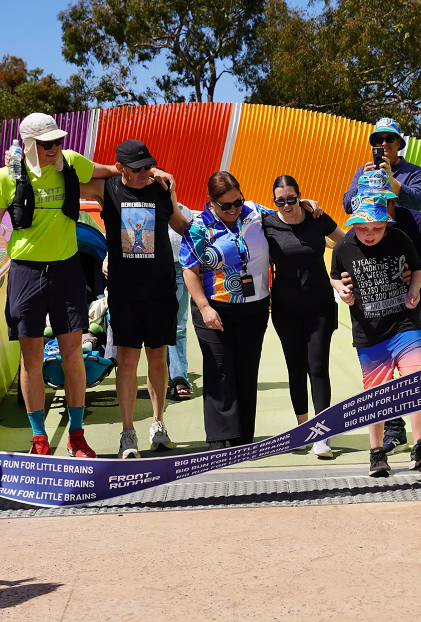 A marathon runner crossing the finish line of his last race with members of the childhood cancer community.