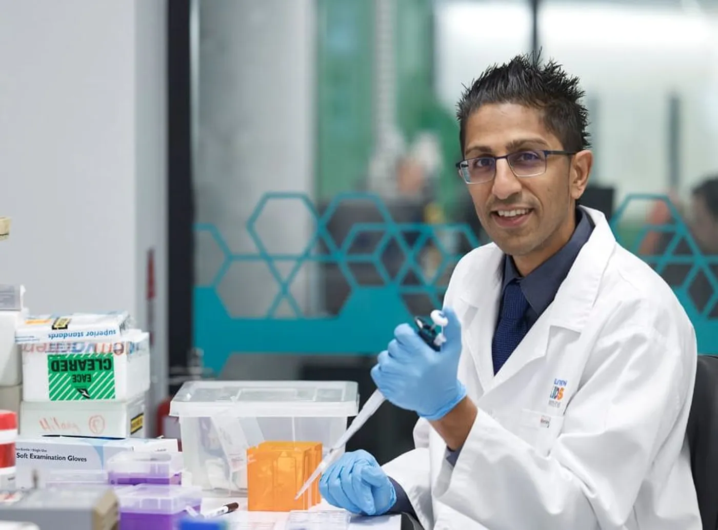 A researcher wearing gloves and a lab coat works with scientific equipment and samples in a medical research laboratory.