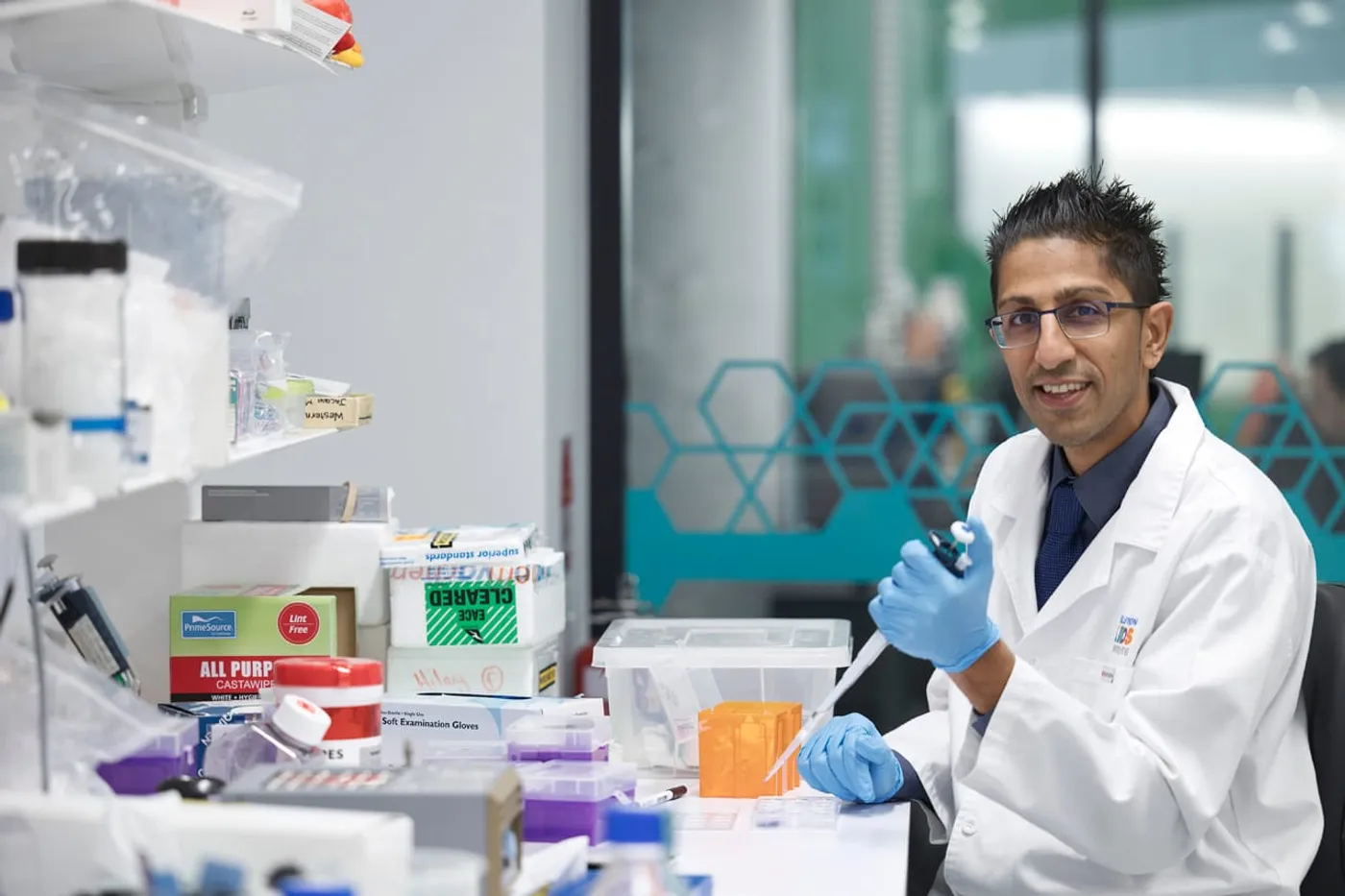 A researcher wearing gloves and a lab coat works with scientific equipment and samples in a medical research laboratory.