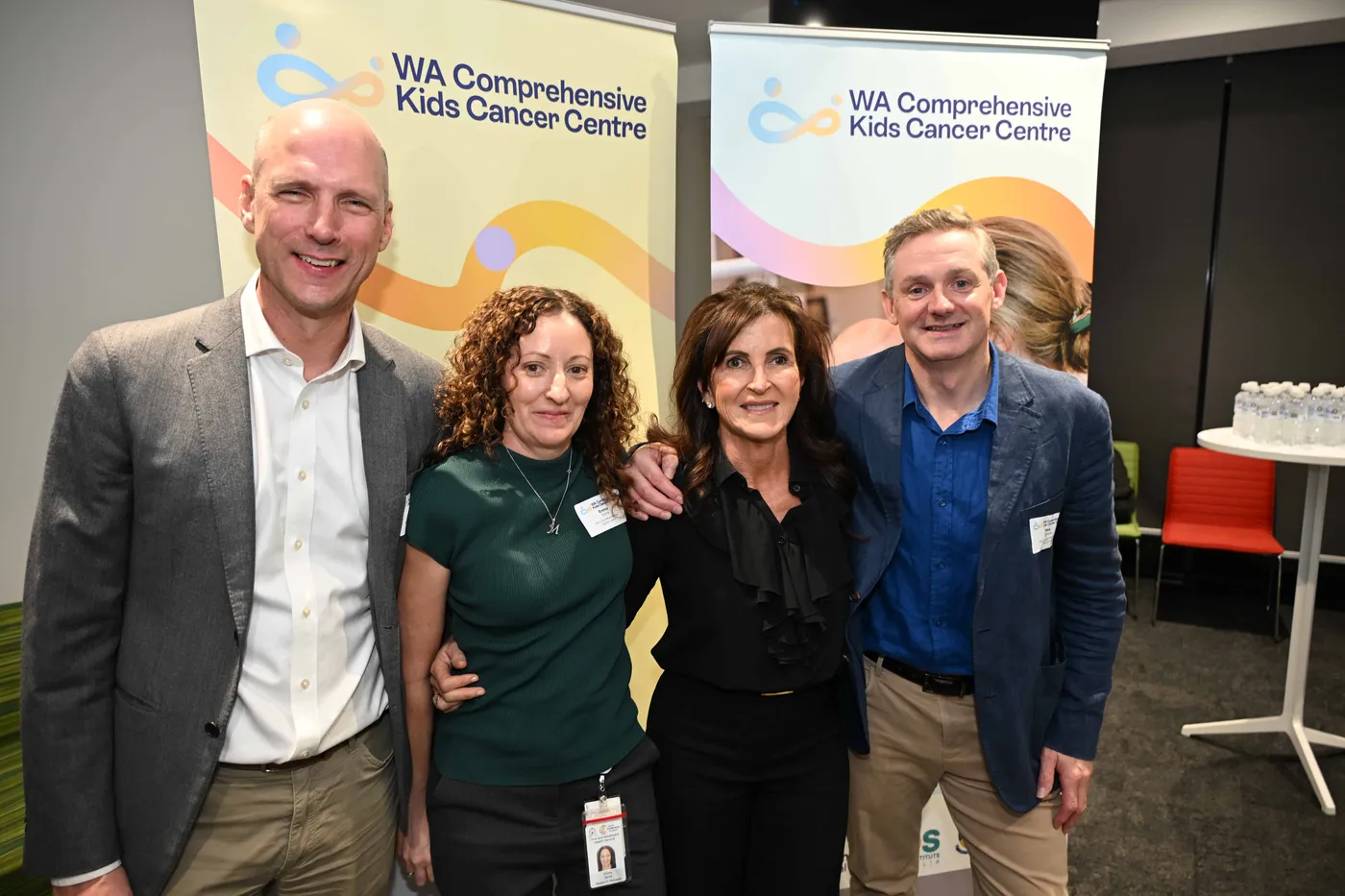 4 people standing together in front of WA Comprehensive Kids Cancer Centre banners.