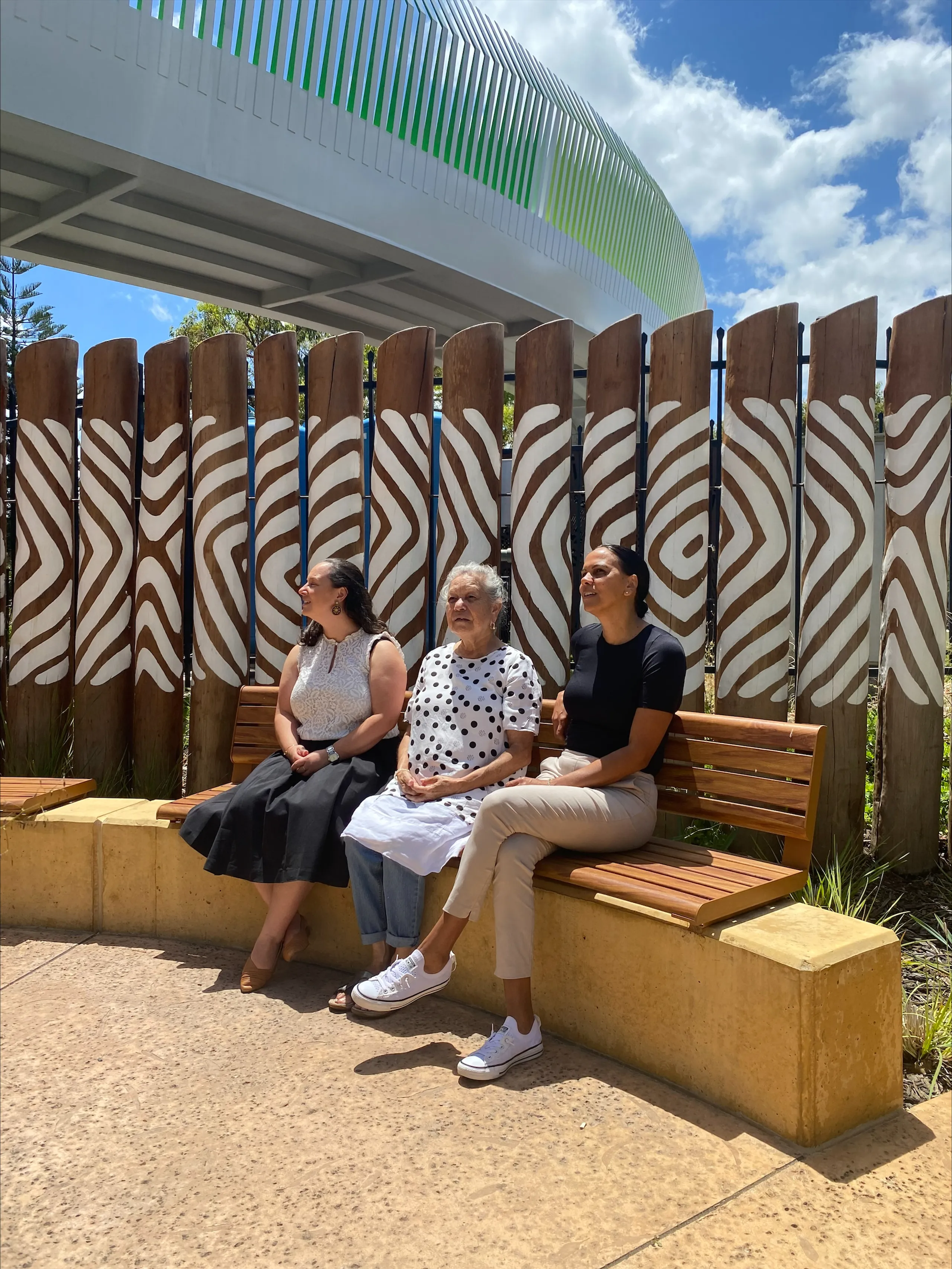 Three people sitting on a bench looking up