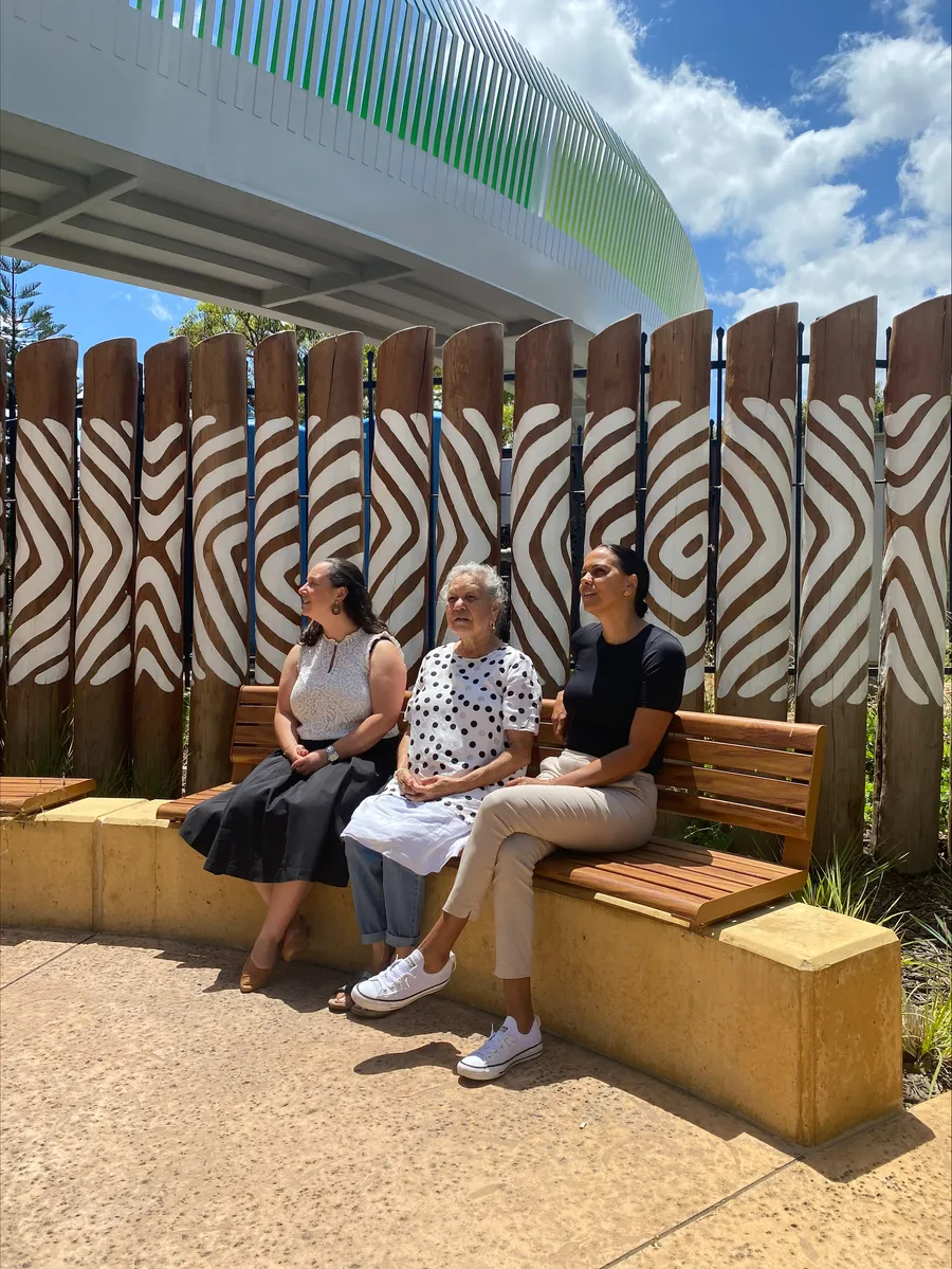 Three people sitting on a bench looking up