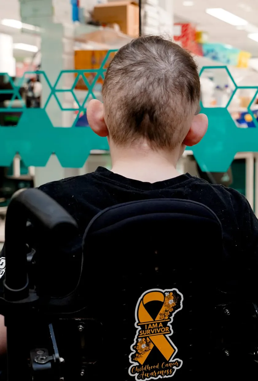 a young boy in a wheelchair looking at a research lab.
