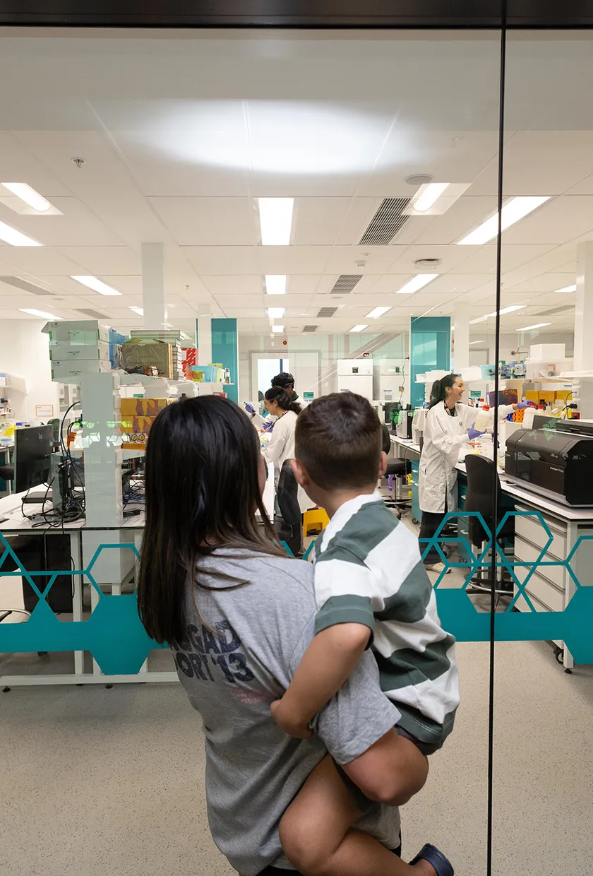 Mum holding son up looking into a cancer lab