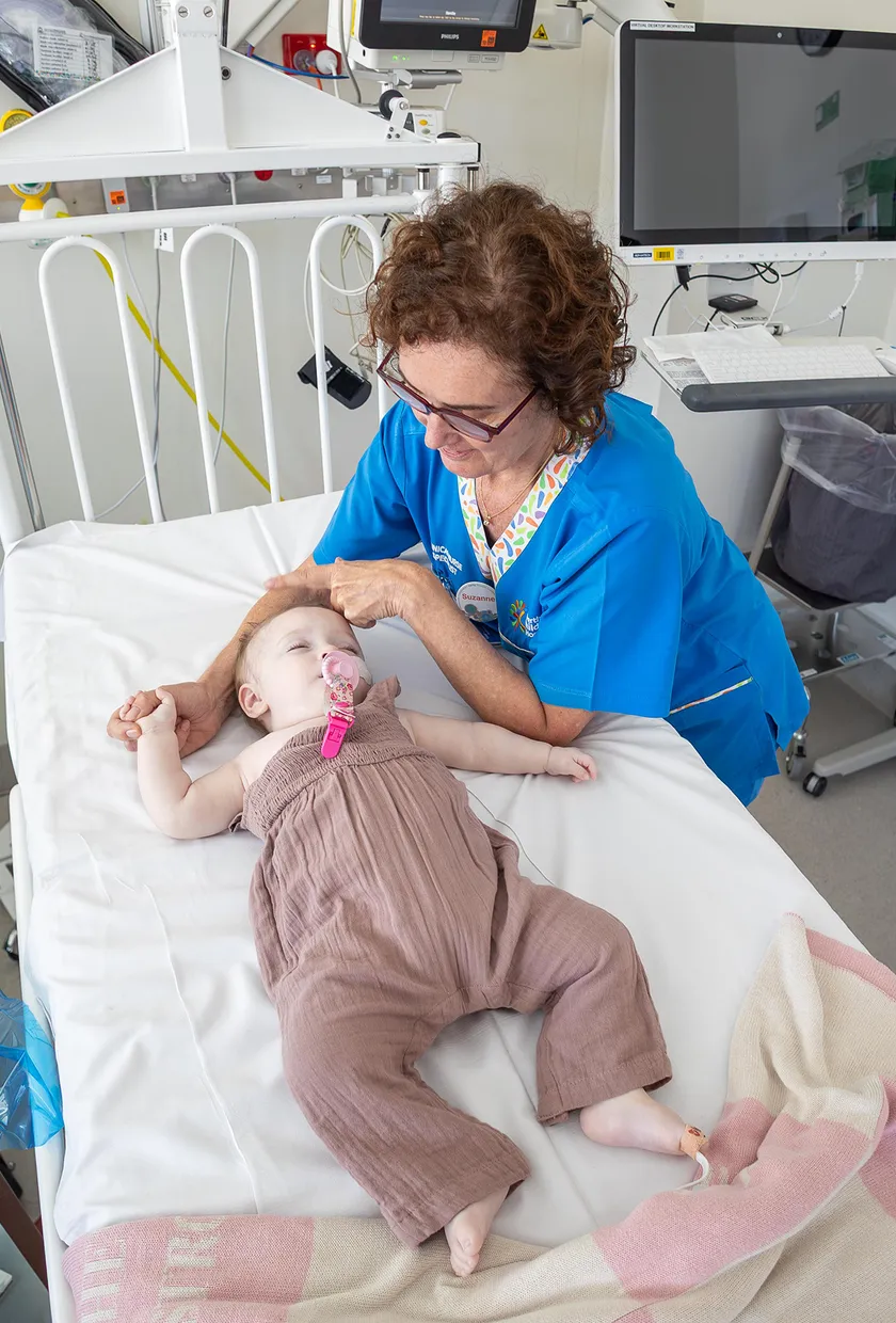 A little baby in a hospital bed being taken care of by a nurse.