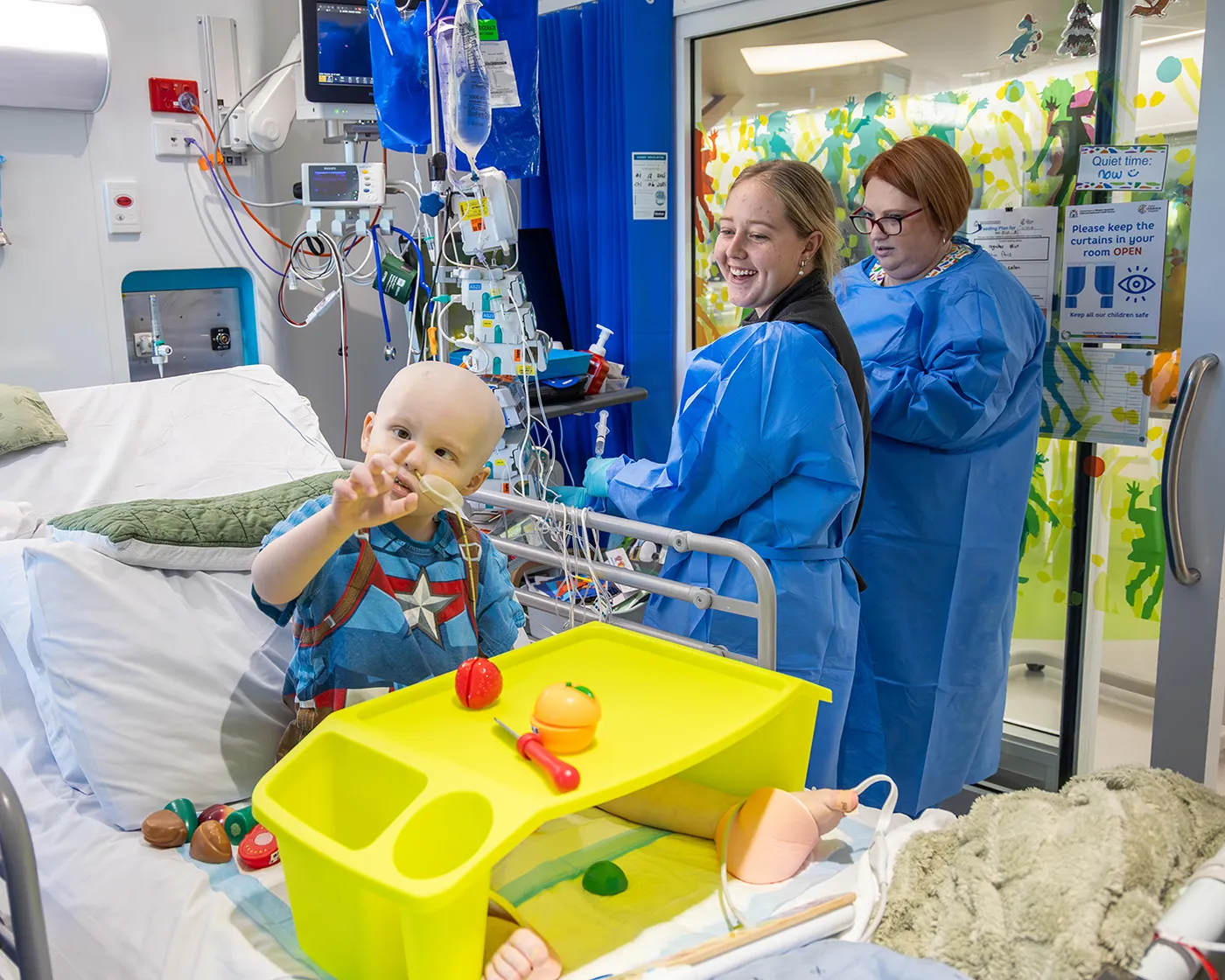 a little boy in a hospital bed waving