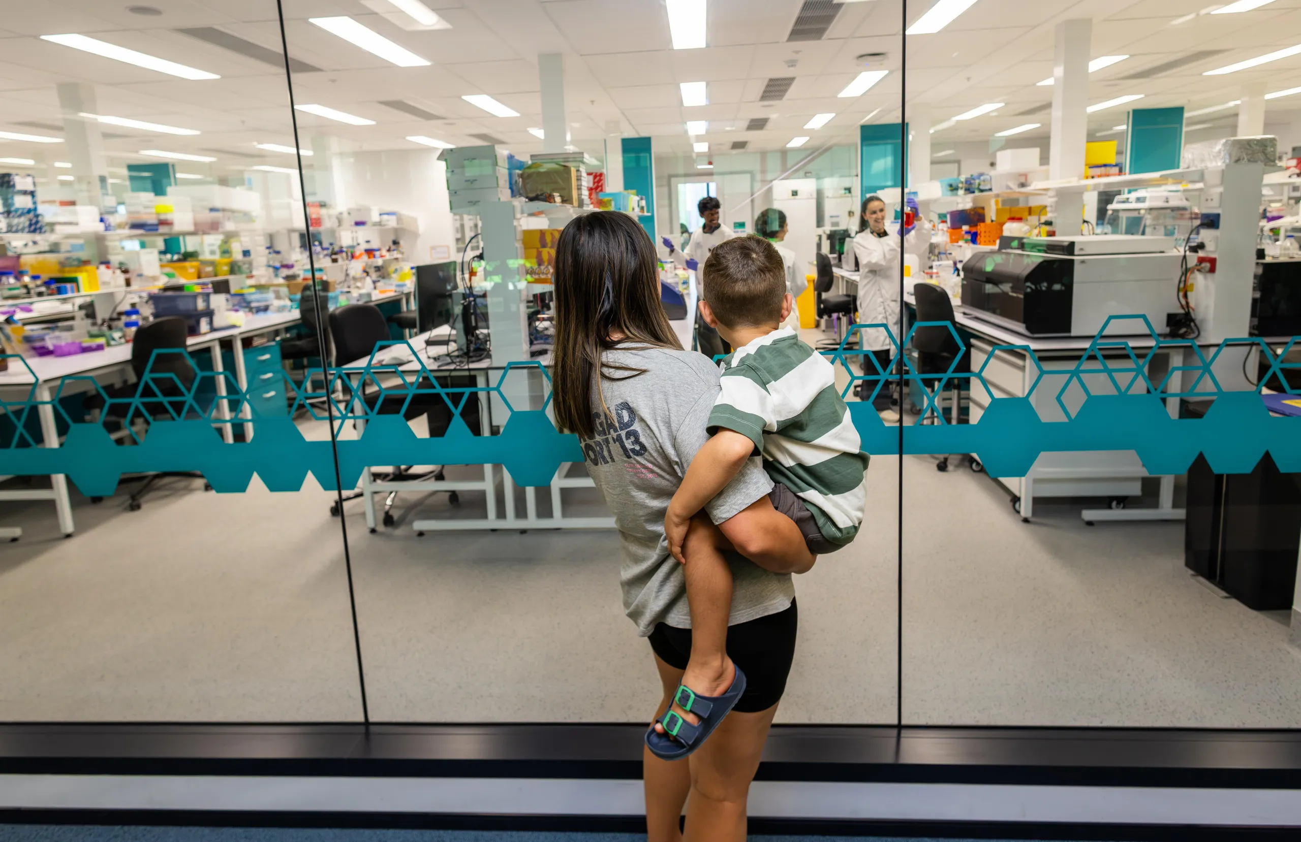 A mother and son looking into a cancer research lab.