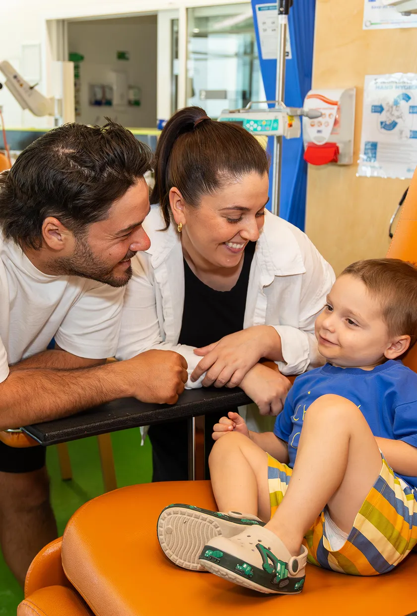 two parents smiling at their son in a big orange chair