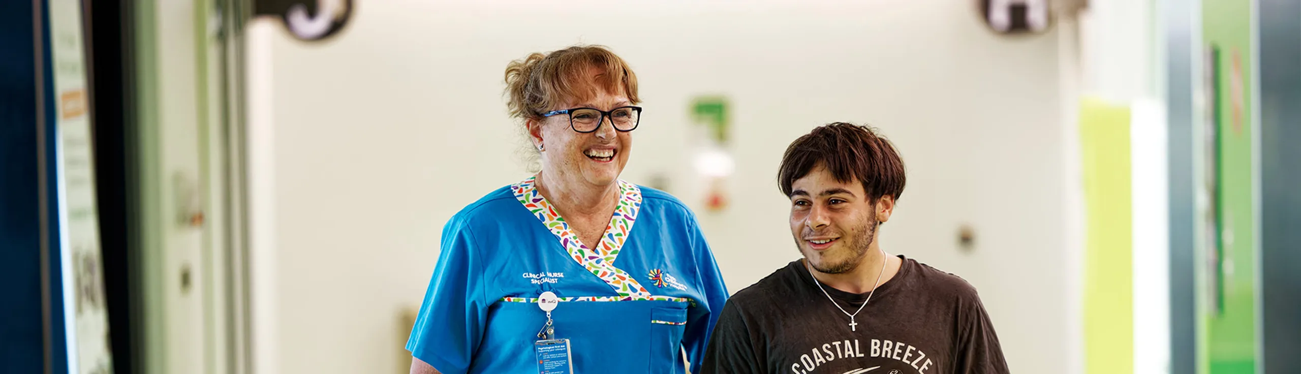 A nurse and adolescent patient walking together.